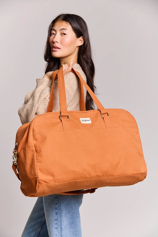 Model carrying Hindbag Yves XL travel bag in Sienna organic cotton